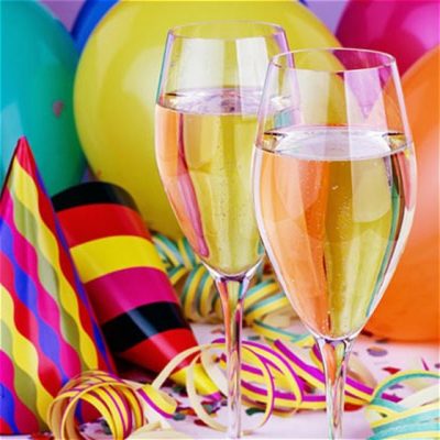 Two glasses of champagne among party hats and balloons