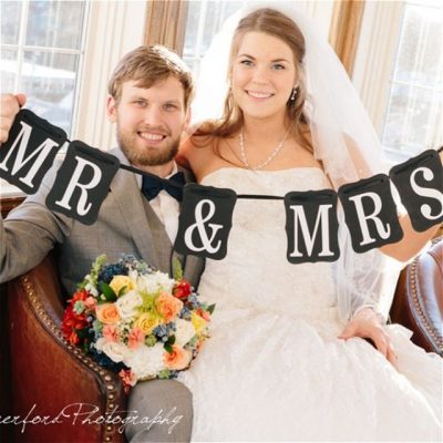 Newlyweds holding a banner that reads Mr and Mrs